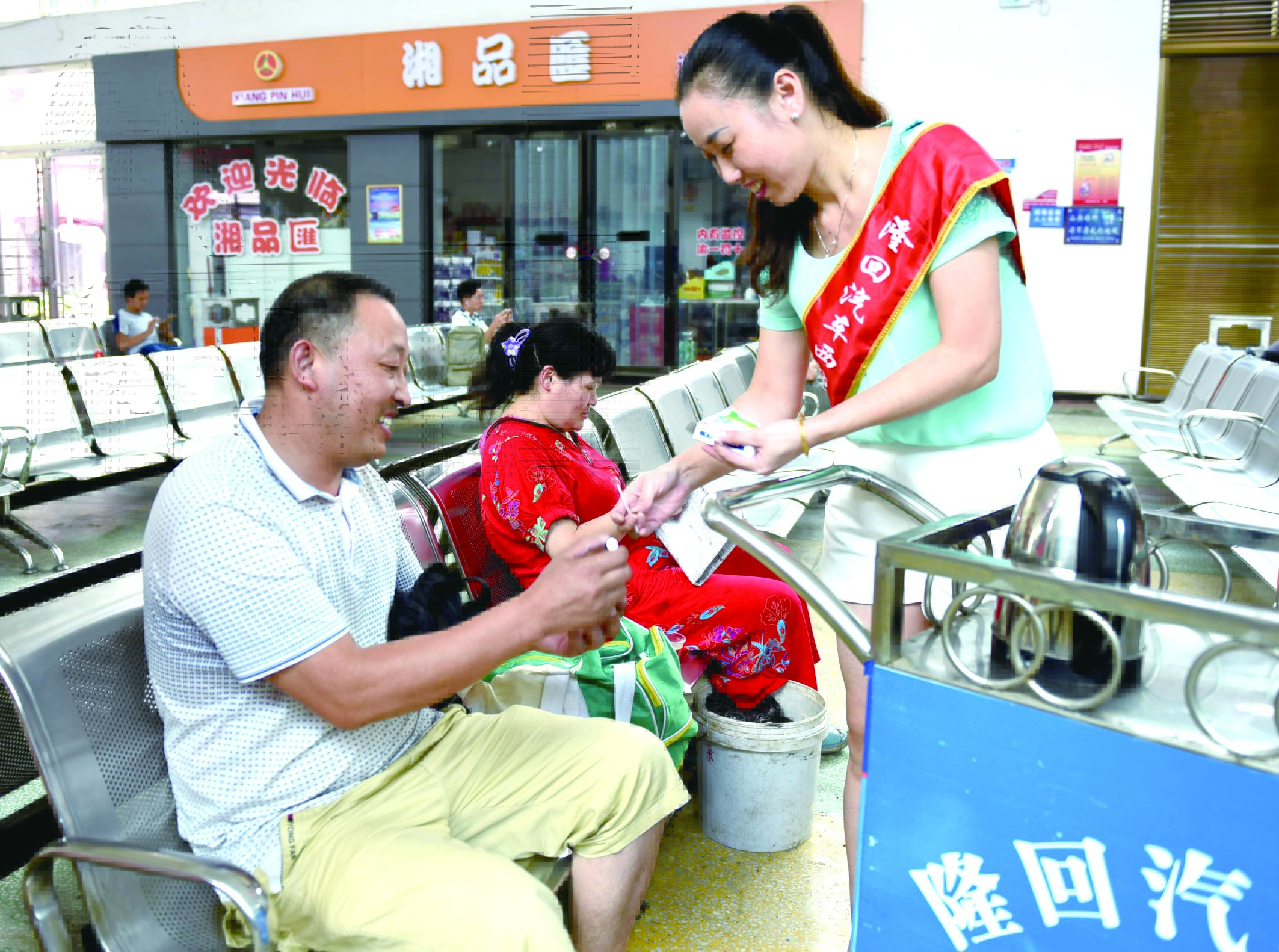 隆回分公司汽車西站工作人員正在為旅客免費(fèi)贈(zèng)送藿香正氣水。